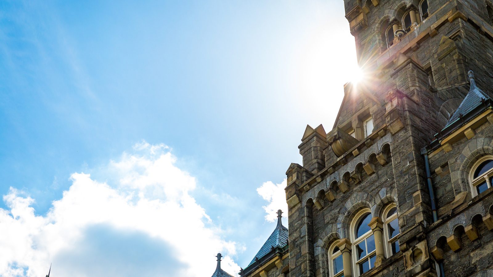 An image of Healy Hall with a sun flare peeking out from behind the clock tower
