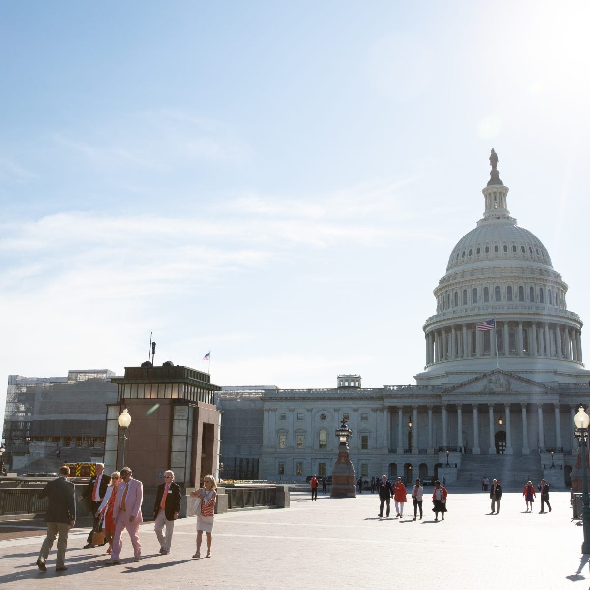 A small crowd walks outside of the Capitol Building