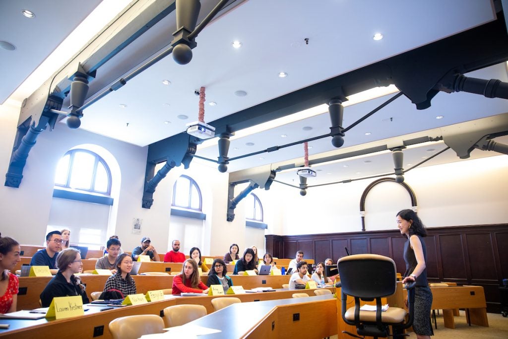 Graduate students sit in a classroom while a professor teaches