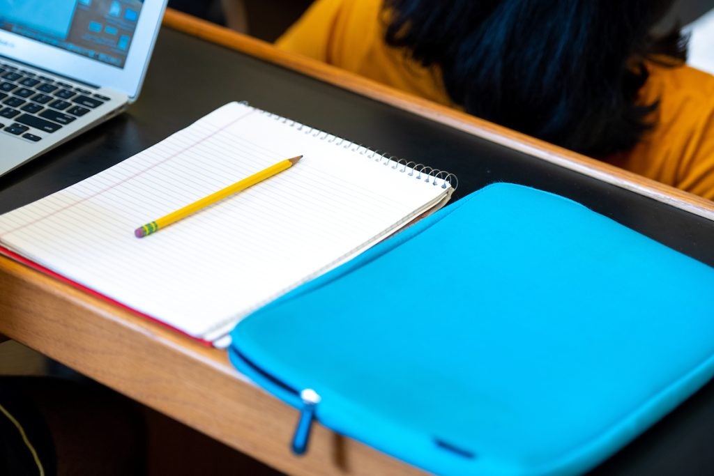 A notebook, pencil and laptop case sit on a table