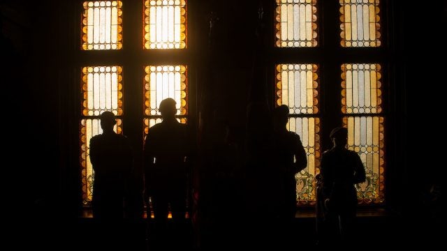 ROTC students in silhouette against light from stain glass windows in Gaston Hall