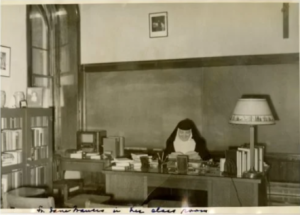 Sr. Jane Frances Liebell sits at her desk wearing a nun's habit