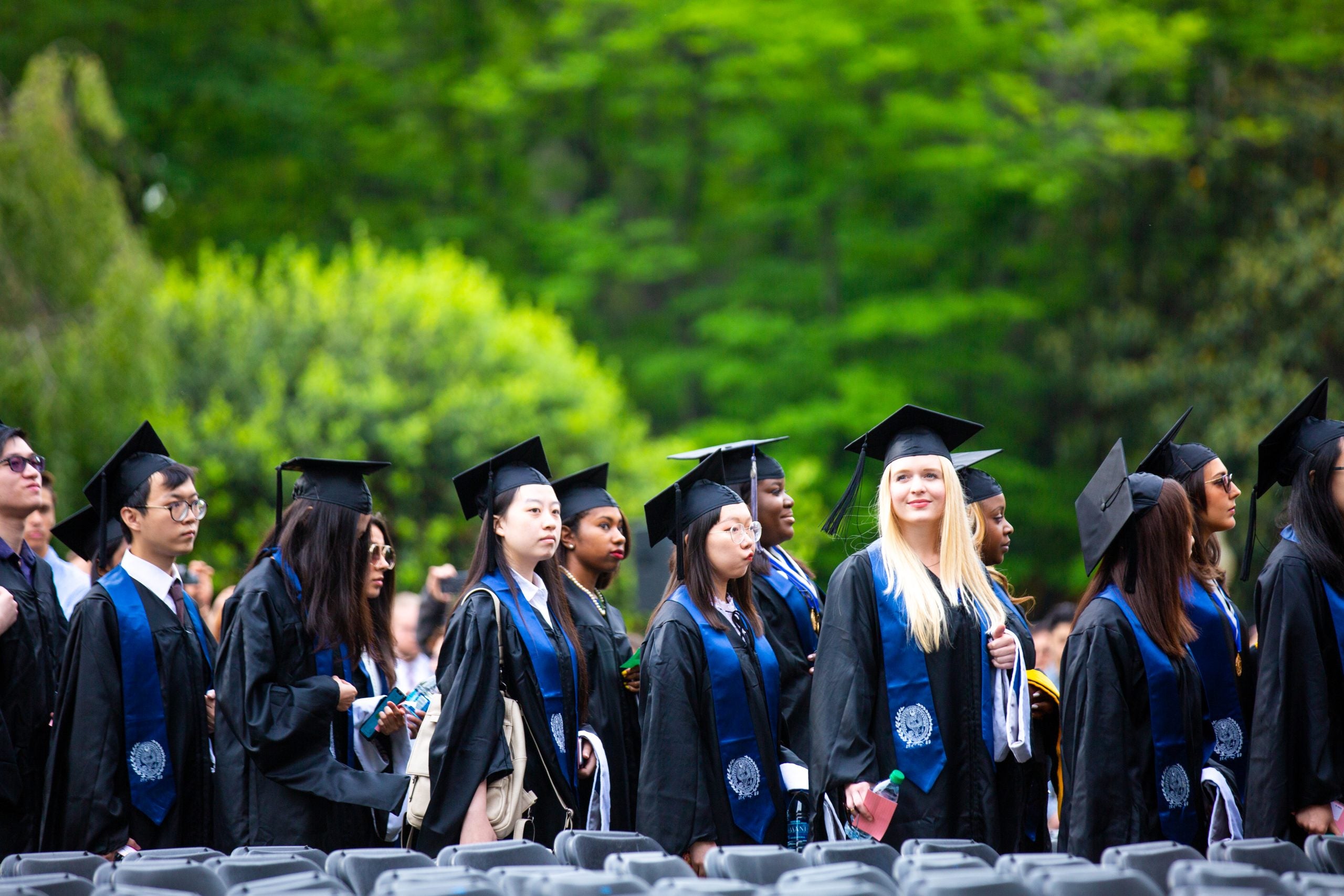 Graduate students wearing academic regalia line up on Healy Lawn for the Commencement Ceremony in 2019