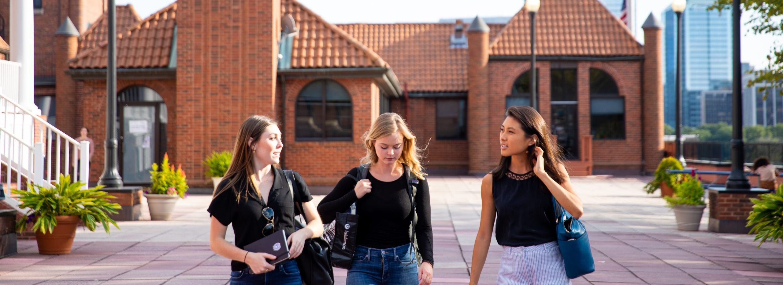 Three graduate students walk toward Prospect Street across rooftop patio of Car Barn