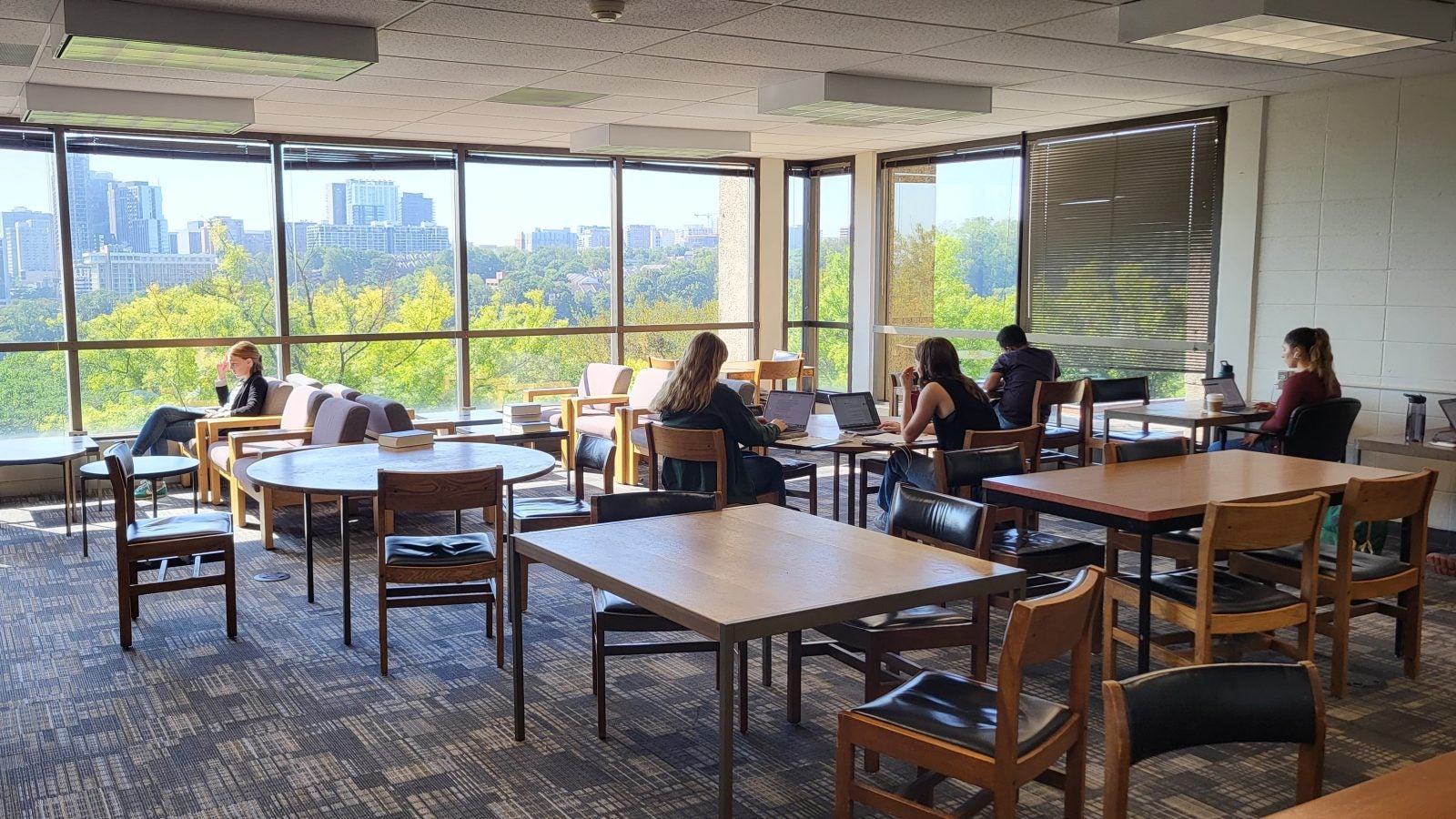 Students sit around square tables inside a graduate student study room in Lauinger Library