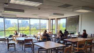 Students sit around square tables inside a graduate student study room in Lauinger Library