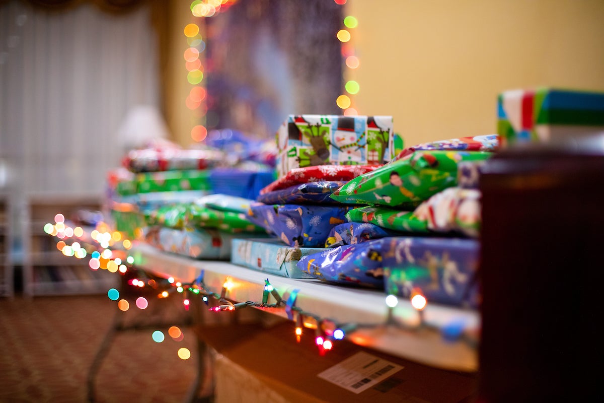 Gifts covered in colorful wrapping paper on top of a table with a string of twinkling lights