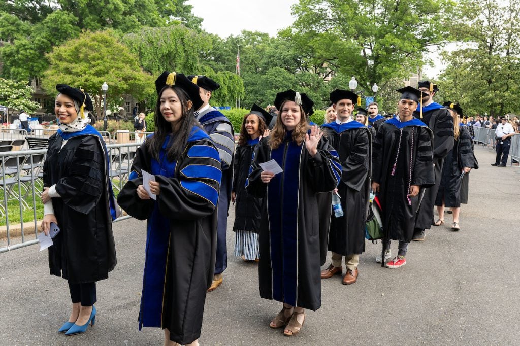 Two rows of doctoral candidates wearing their graduation robes stand in line to process into the Graduate School Commencement Ceremony in 2023