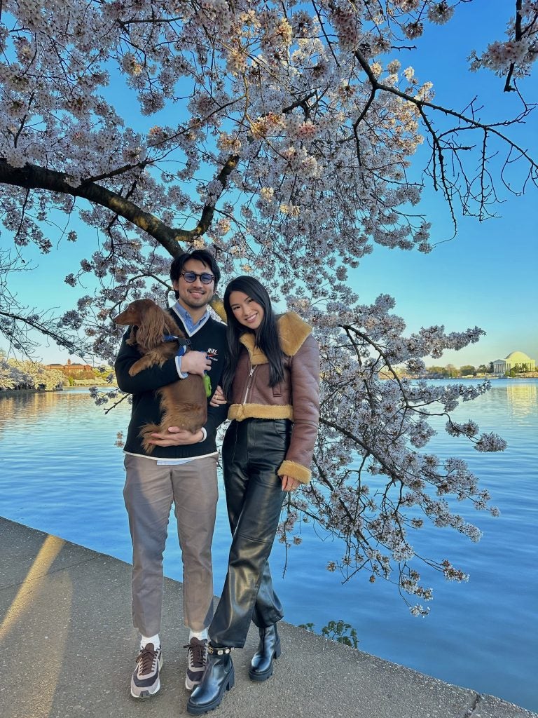 Ken Hoang and Kenzie Lau-Kee in front of a cherry blossom tree at the Tidal Basin