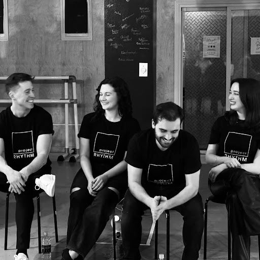 Black and white photo of four people sitting in chairs laughing with each other