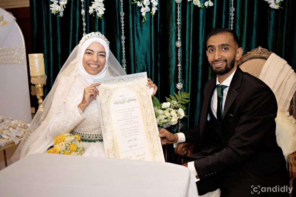 Abrar Omeish (left) and Umar Shareef (right) dressed in wedding clothes, smile as they hold up their wedding certificate