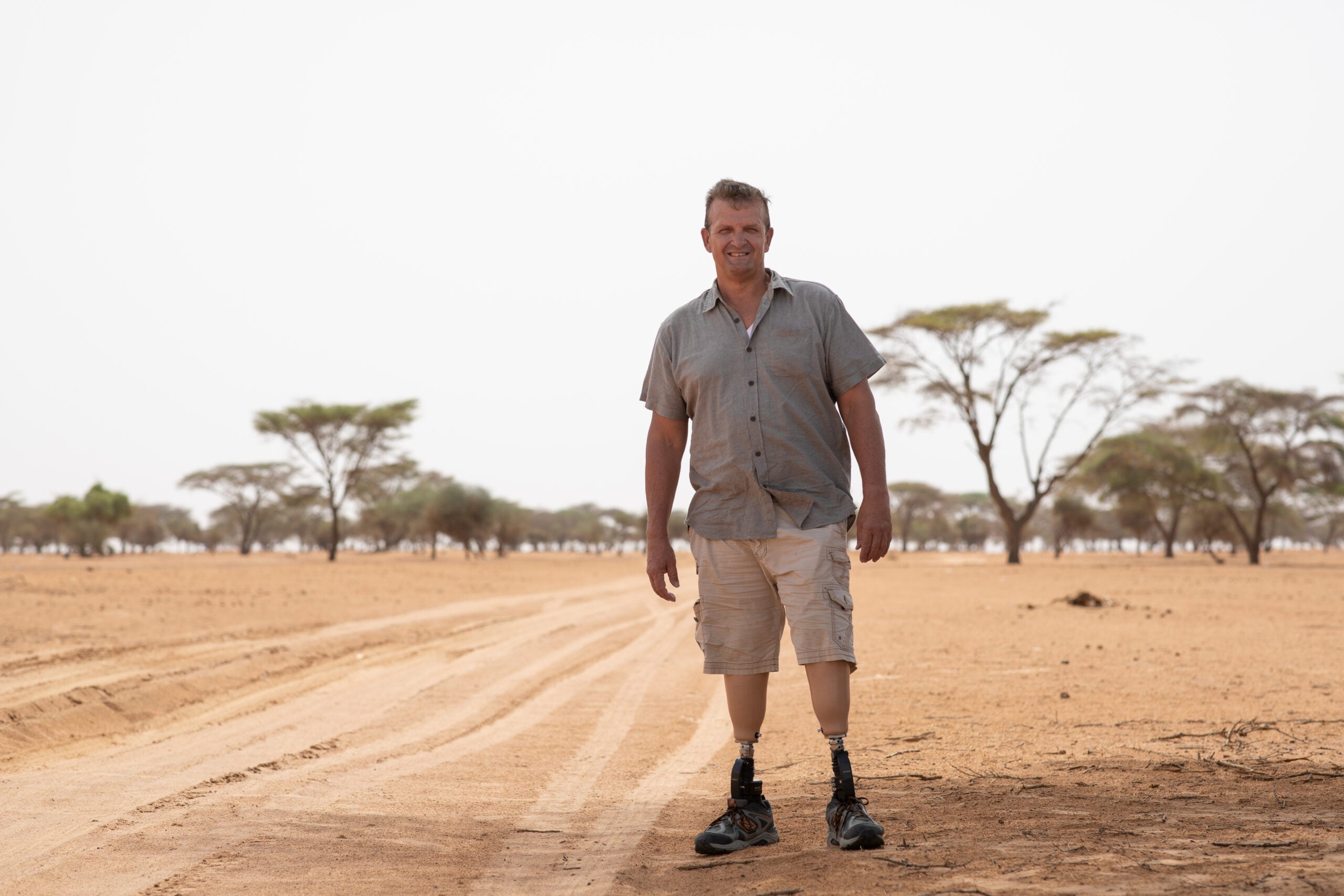 Ken Rutherfod (G'00) stands on his two prosthetic legs on a dusty road in Africa