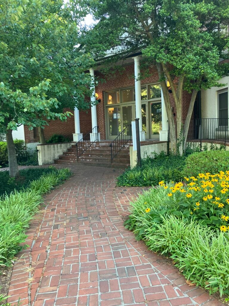 Exterior of Lindamood-Bell Center; brick walkway surrounded by trees and steps leading up to a porch and glass doors