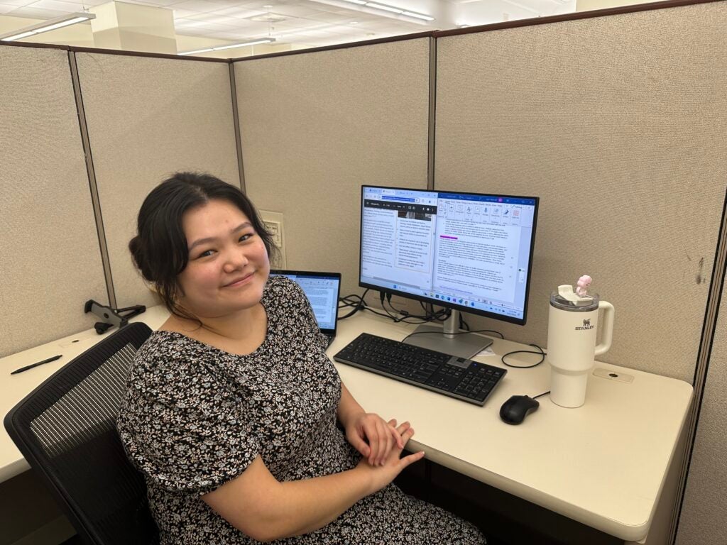 Hannah Kim (left) smiles while seated at her cubicle during her EPA internship