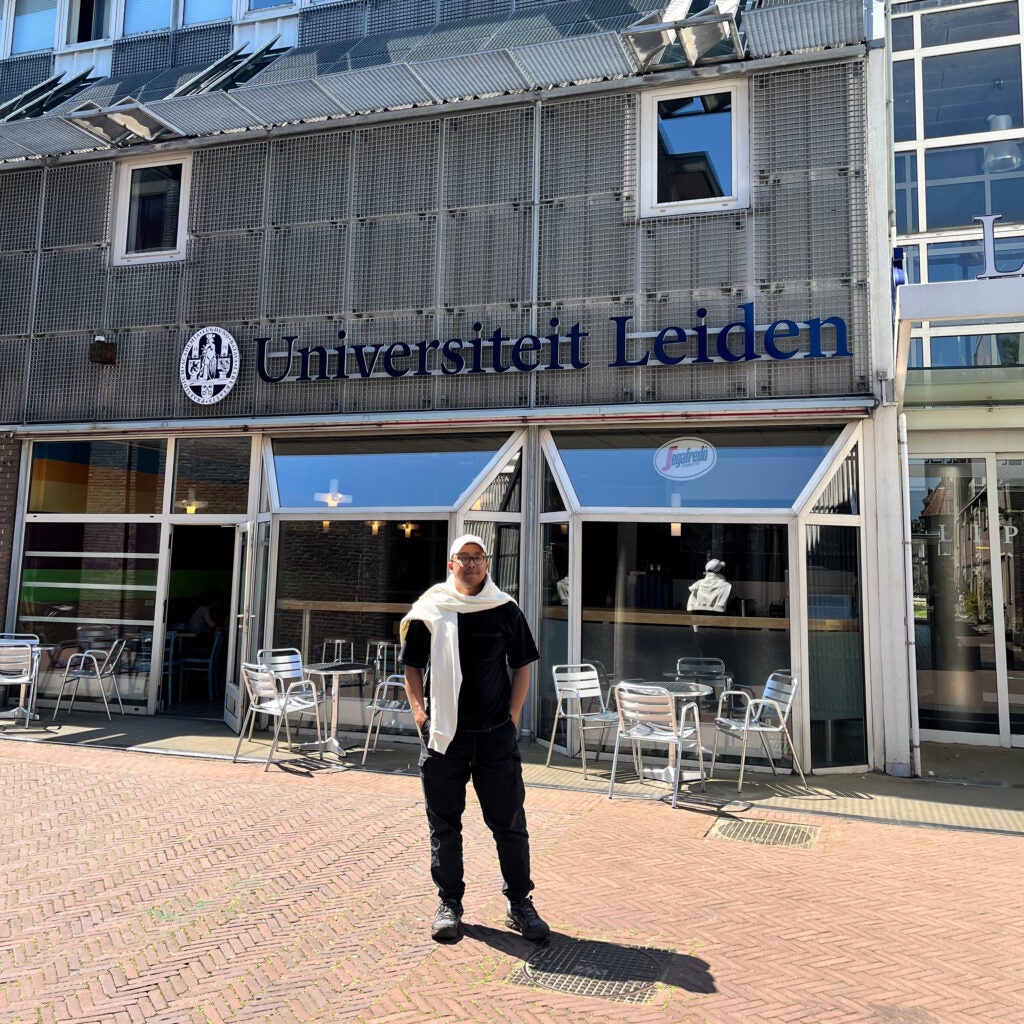 Khoiri stands in front of a building with a sign that reads, "Universiteit Leiden"