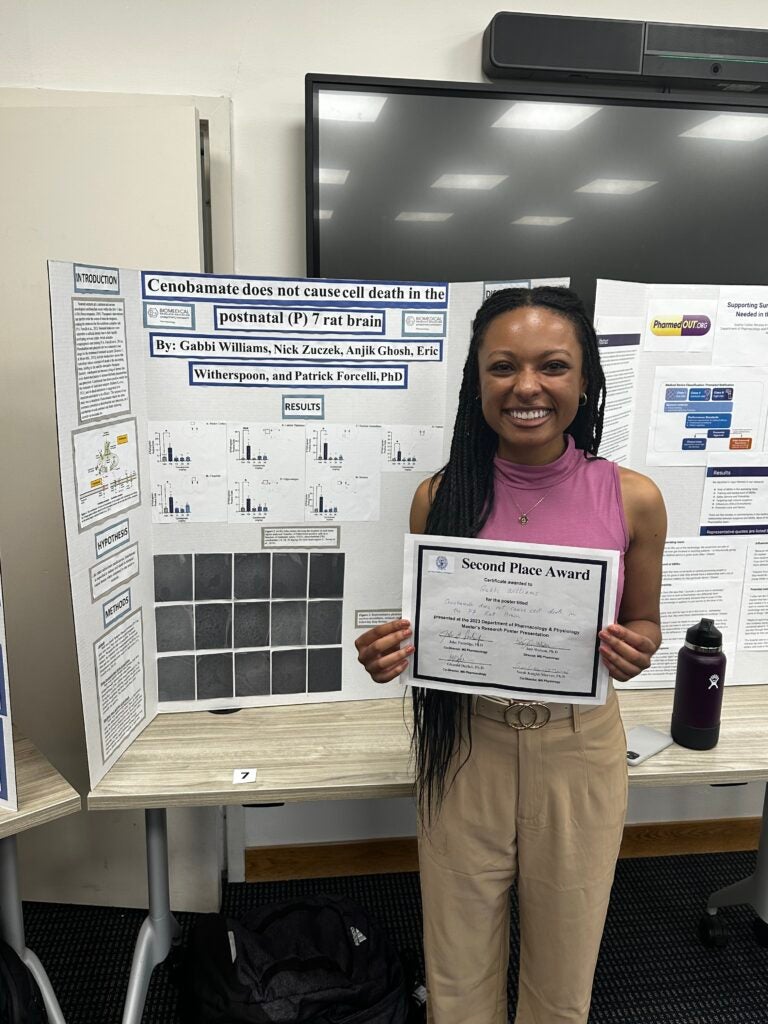 Williams holds a second place award certificate in front of her research poster