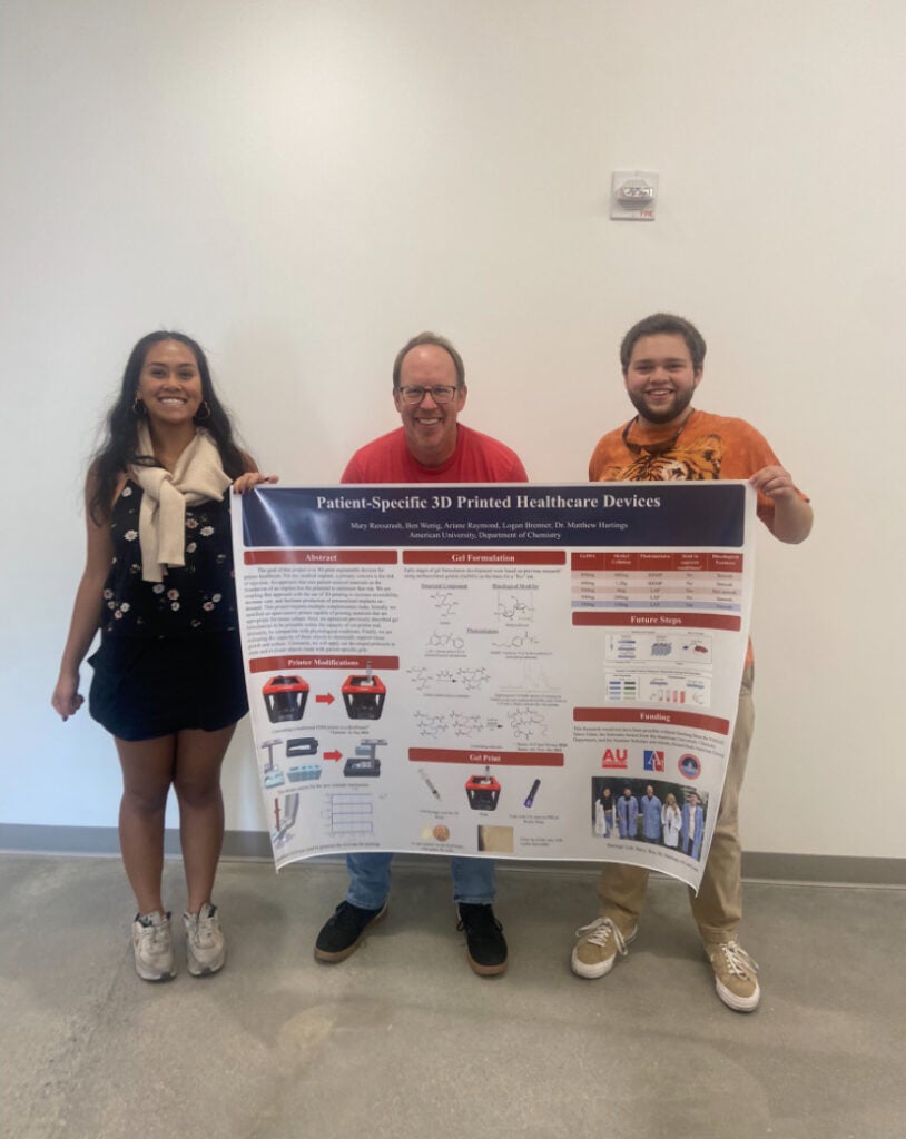 Ruxsarash (left) poses with mentor and classmate holding findings displayed on a research poster