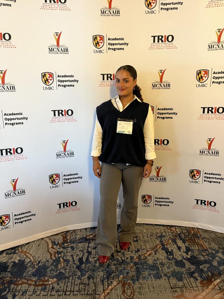 Lugo in front of step-and-repeat banner at UMBC conference