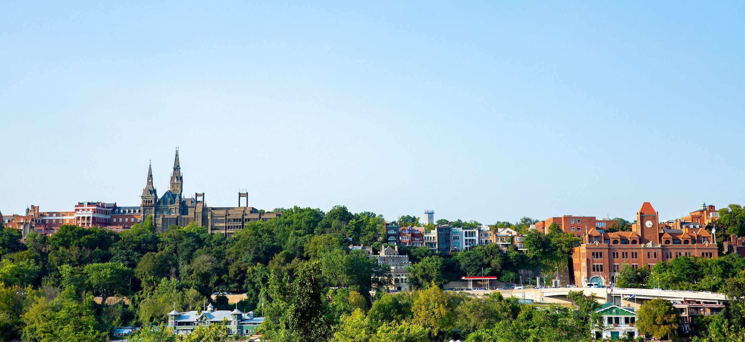 A landscape photo of Georgetown University as seen from across the Potomac River. Healy Hall is visible at the left, and the Car Barn is visible at the right.