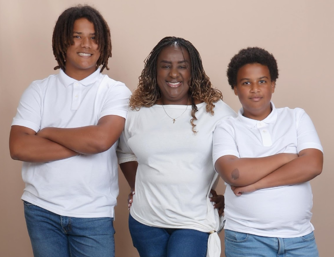 Martha Cameron poses in between her teenage sons in front of a blank portrait backdrop.