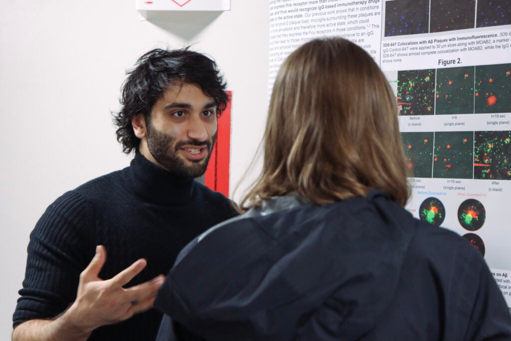A male student talks with an attendee during the poster session.