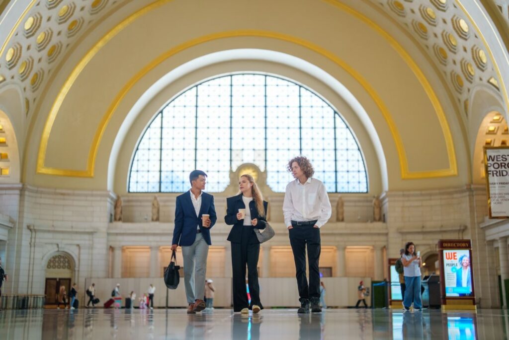 Three people walk side-by-side in professional clothing in Washington, DC's Union Station.