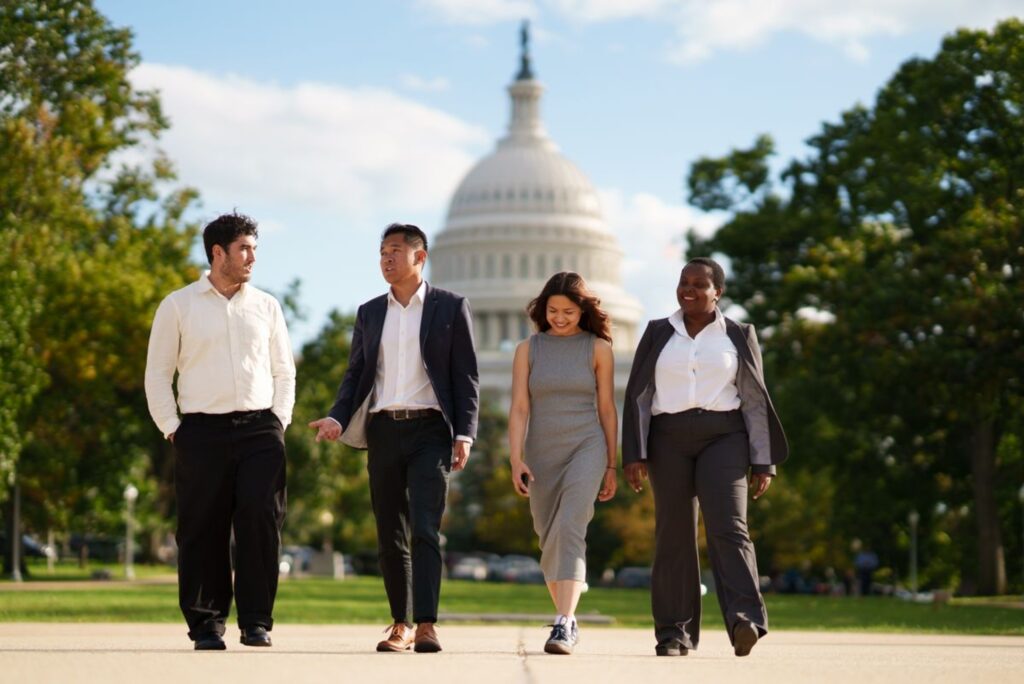 Four students walk in professional clothing outside the U.S. Capitol.