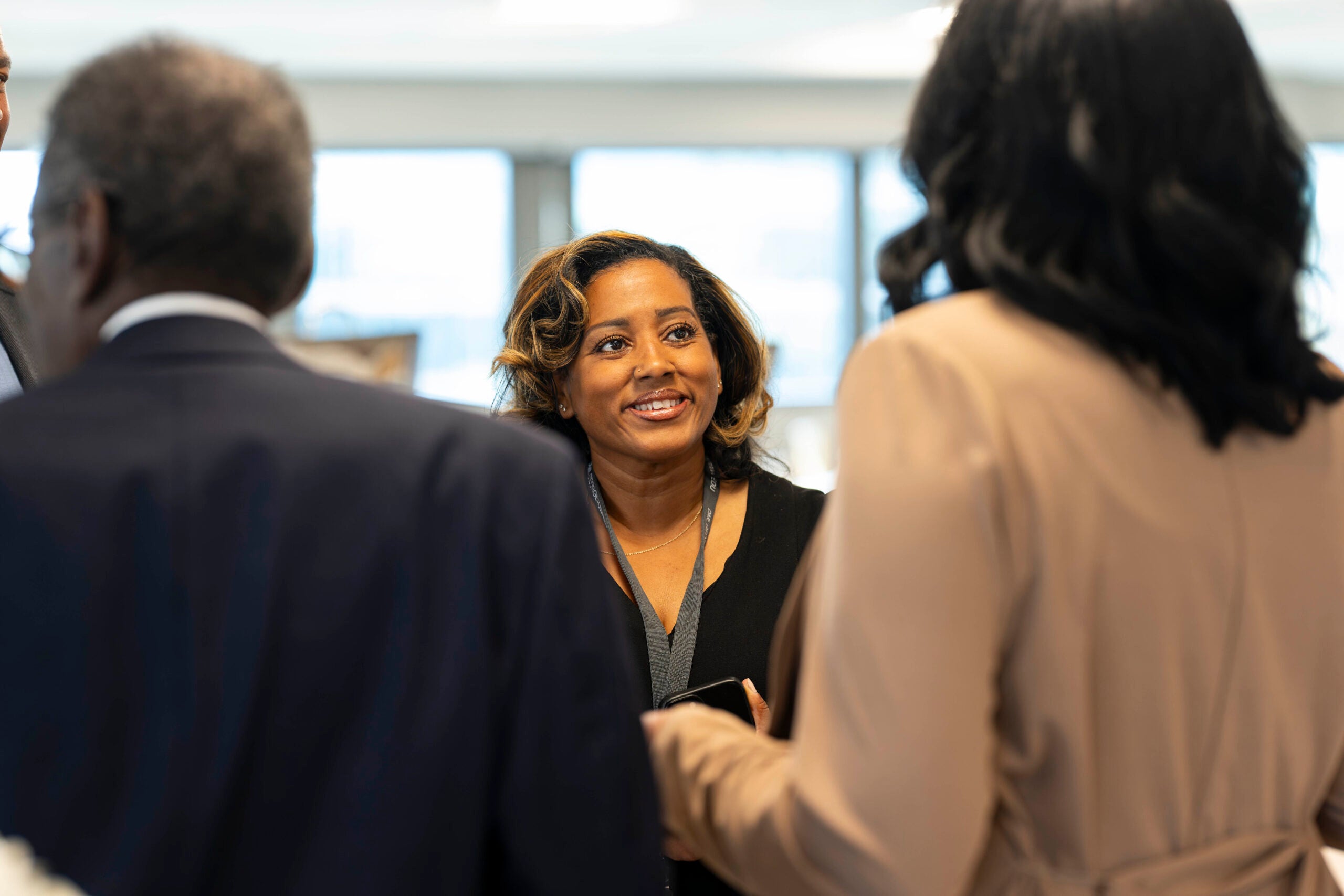 Kenyatta Hazlewood smiles, talking with two people affiliated with the Berkley School of Nursing.