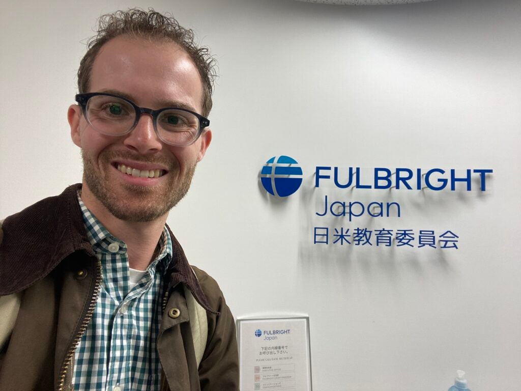 A selfie of Ethan Barkalow with a sign that reads "Fulbright Japan" in both English and Japanese.