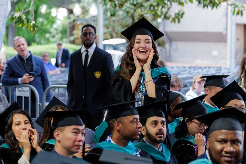 A female student shouts at a loved one in glee at Commencement 2026.