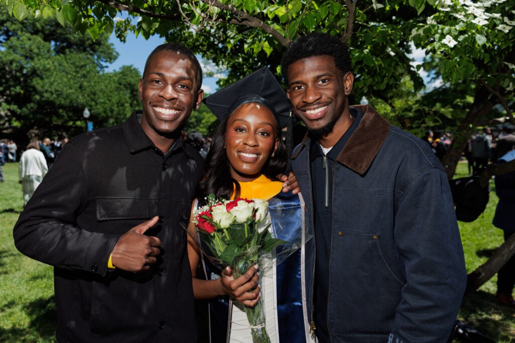 A master's graduate smiles at the camera with two family members.