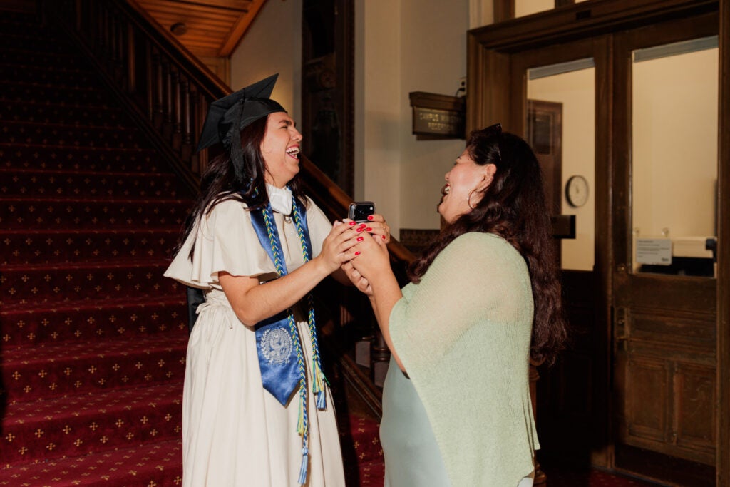 A graduate laughs and clasps hands with a loved one.