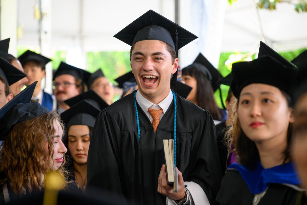 A male master's graduate exclaims in glee as he walks into the Commencement ceremony.