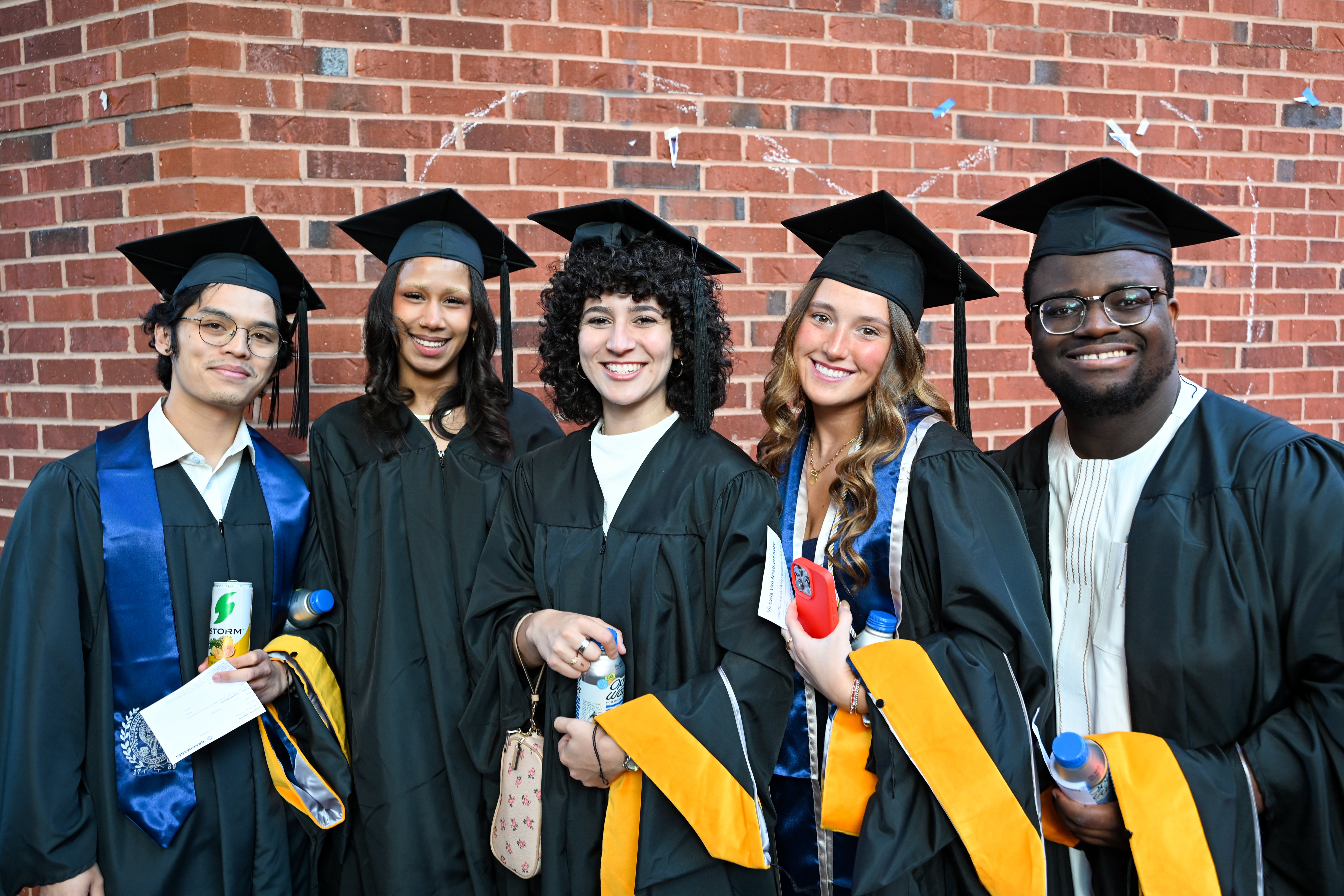 Five Biomedical Graduate Education students pose in a group photo in their grad regalia.