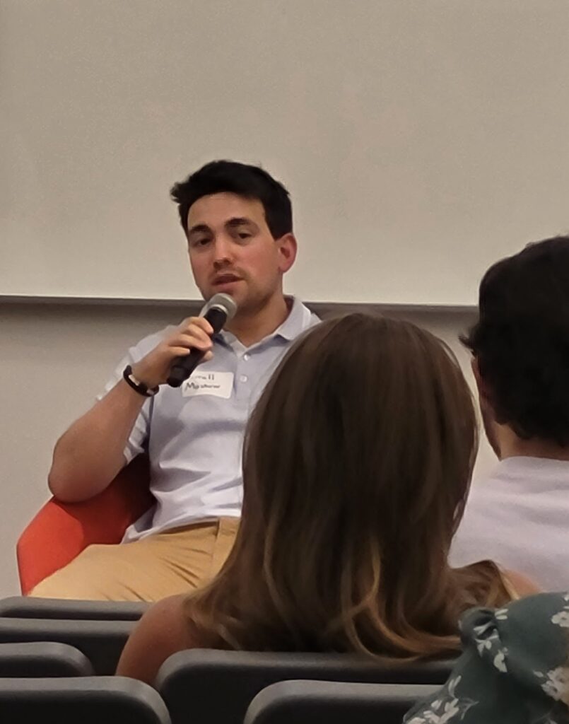 Farrell Moskow holds a microphone at a panel.