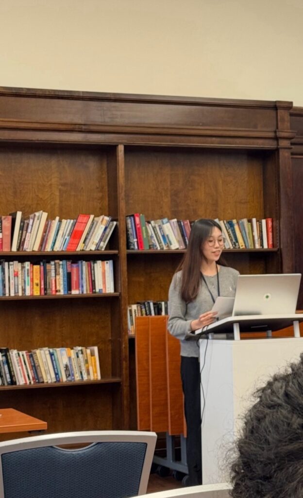 Seyoung Kim presents her research at a lectern in a library.