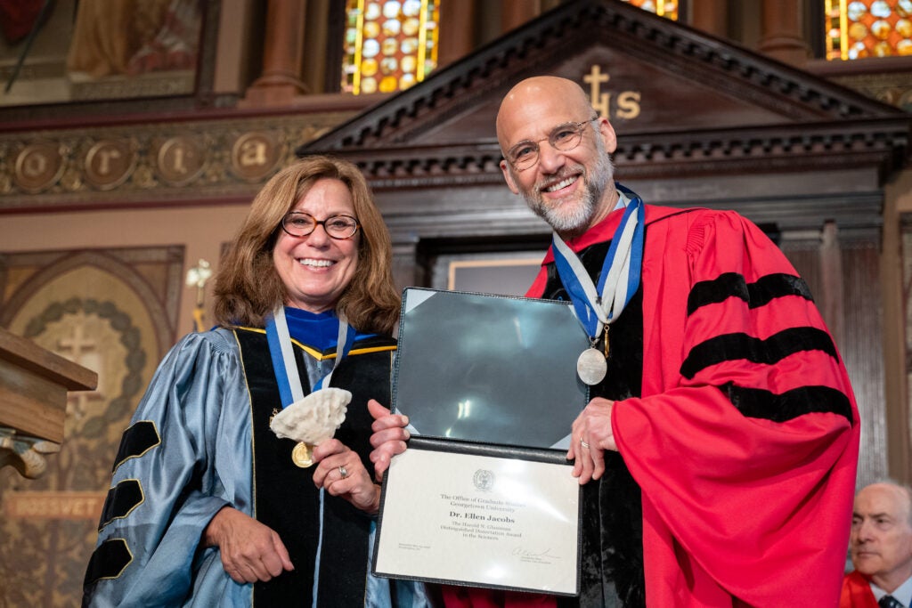 Distinguished University Professor Janet Mann holds a sea sponge in her hand next to Alex Sens, who holds Dr. Ellen Jacobs' framed Glassman Award.