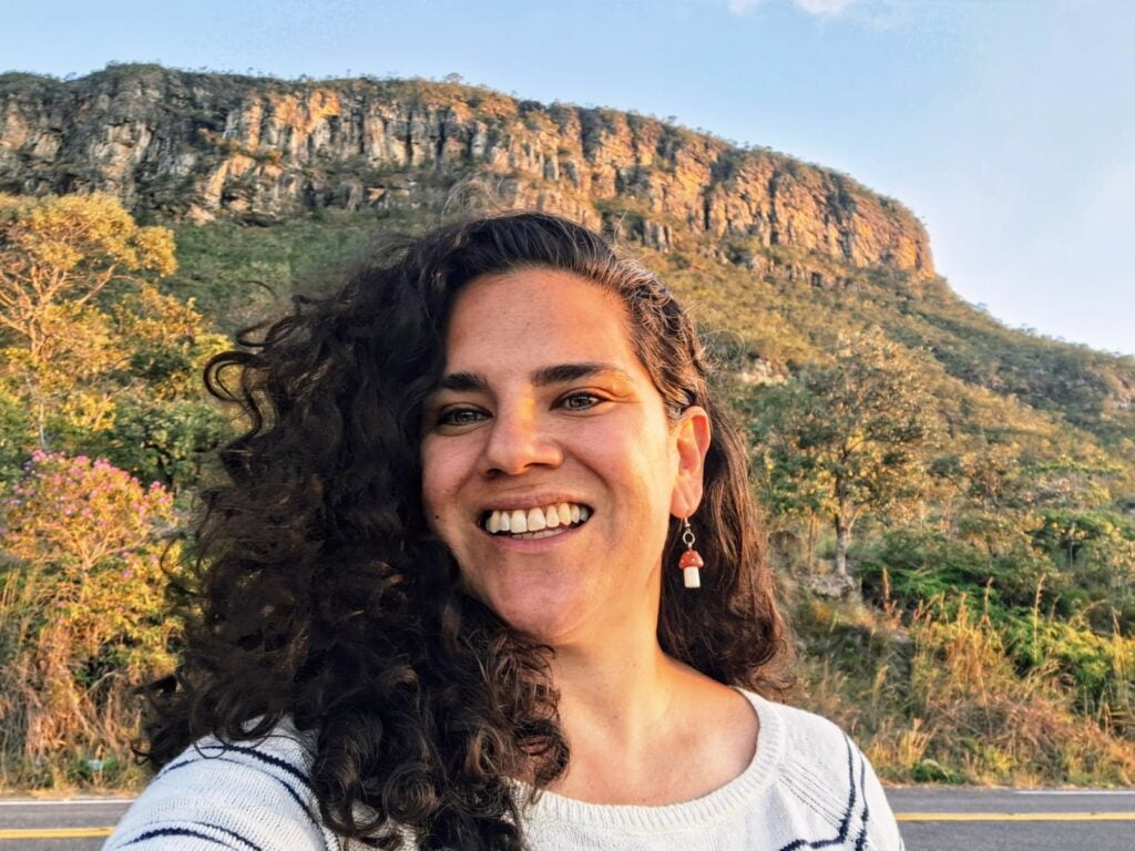A headshot of Natascha de Vasconcellos Otoya in front of a mountainous hill.