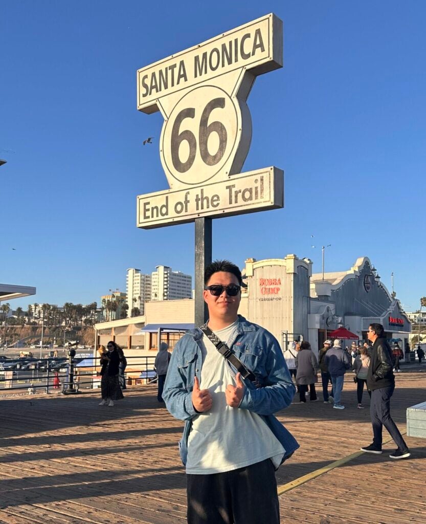 Ph.D. student Kaiyan Shi shows a thumbs up in front of the sign marking the end of Route 66.