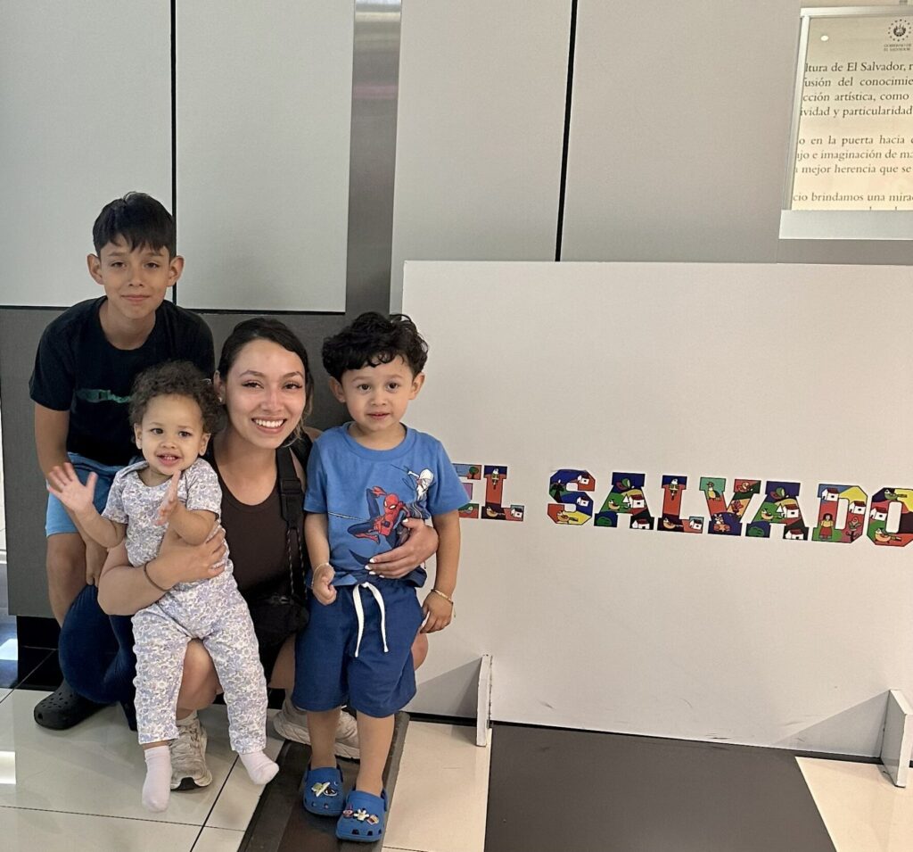 Keiti Lazo poses with three young relatives in front of a sign reading "El Salvador".