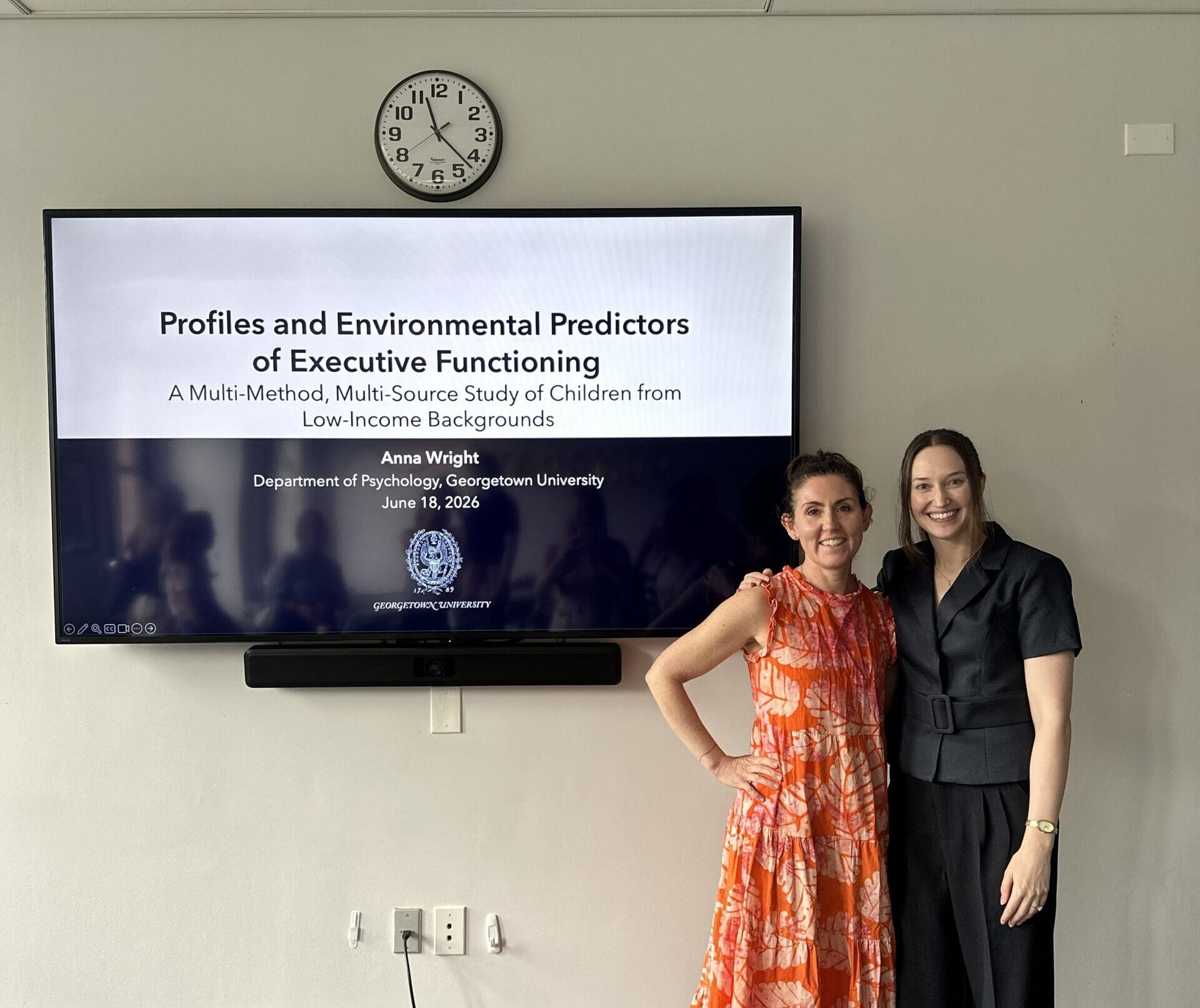 Anna Johnson and Anna Wright stand in front of a screen showing Wright's presentation.