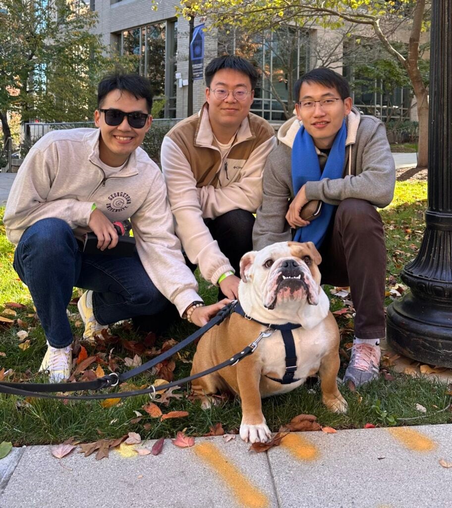 Ph.D. in biostatistics student Kaiyan Shi pets Georgetown mascot Jack the Bulldog with two other friends.