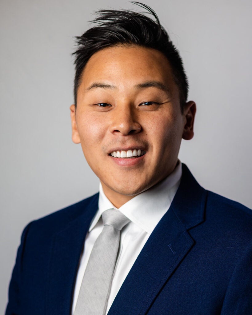 A headshot of Anthony Choi, a man wearing a suit.