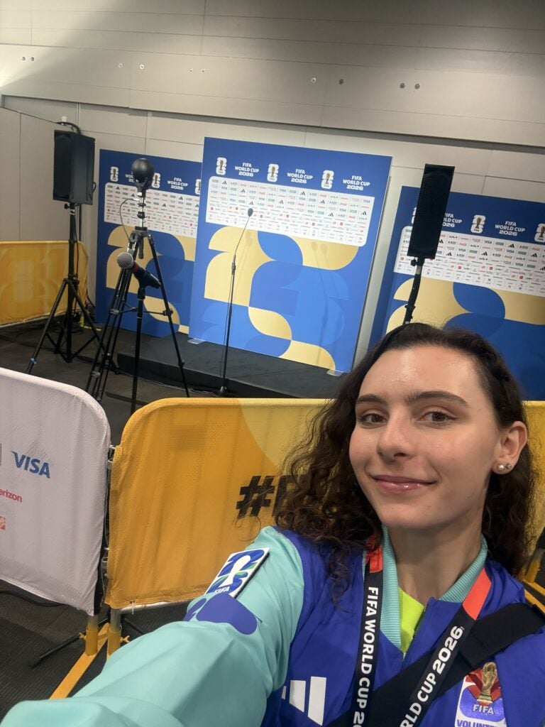 Georgetown Ph.D. student Rachel Beatty takes a selfie in front of a media setup for the FIFA World Cup 2026.