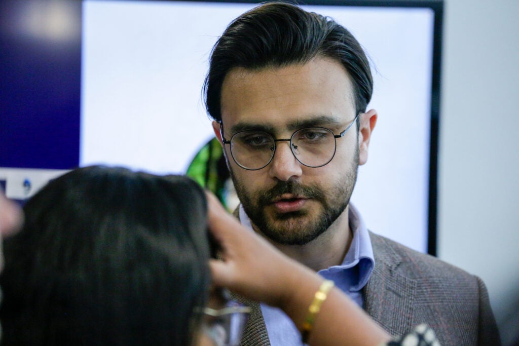 Anees Baig, facing the camera, speaks to someone during his research presentation.